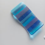Blue and purple striped bar of soap on a light gray background