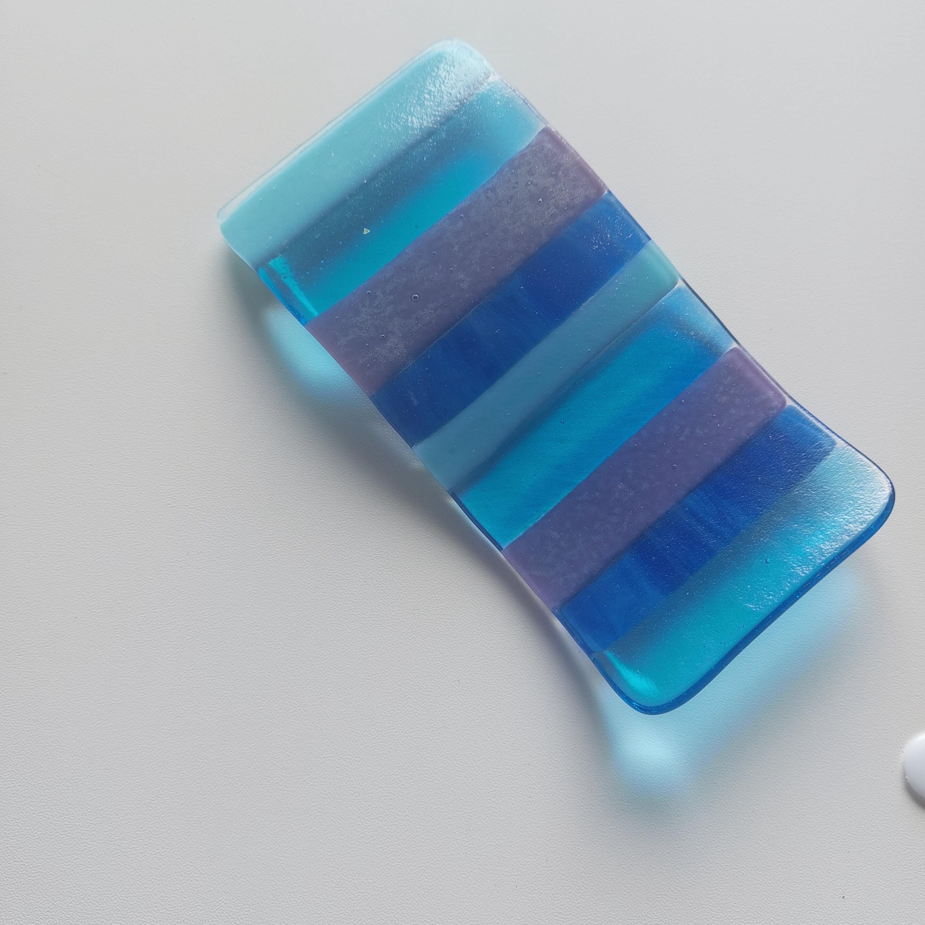 Blue and purple striped bar of soap on a light gray background