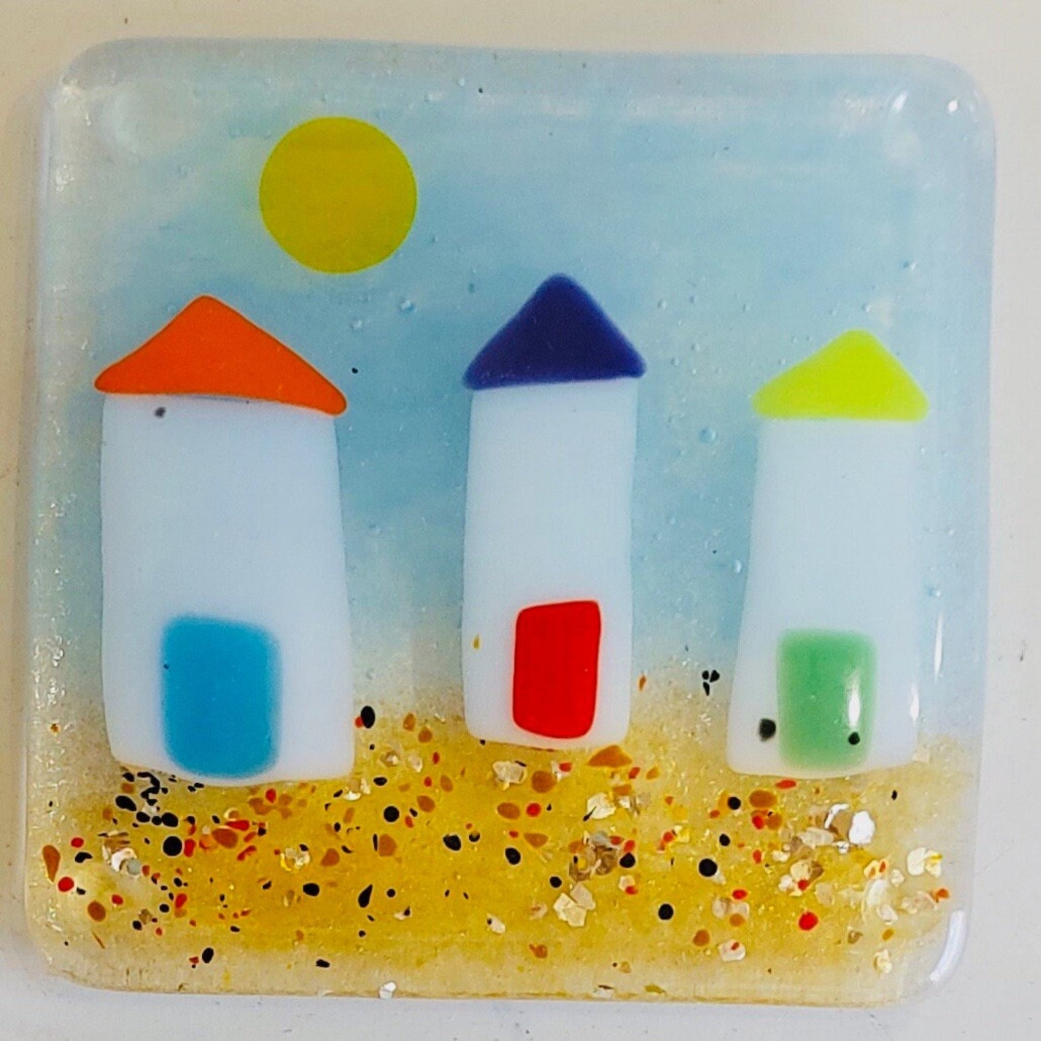 Decorative glass panel with colorful beach huts and a sun on a blue background